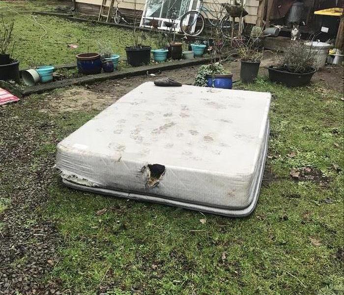 Picture shows a matress out in a front yard that that had caught fire due to a faulty cell phone charger,